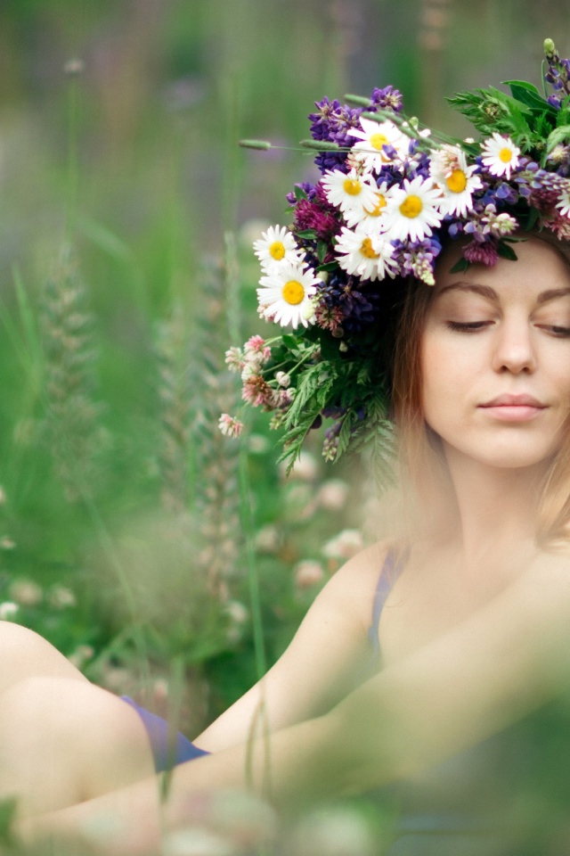Красивая девушка с венком из полевых цветов на голове летом 
