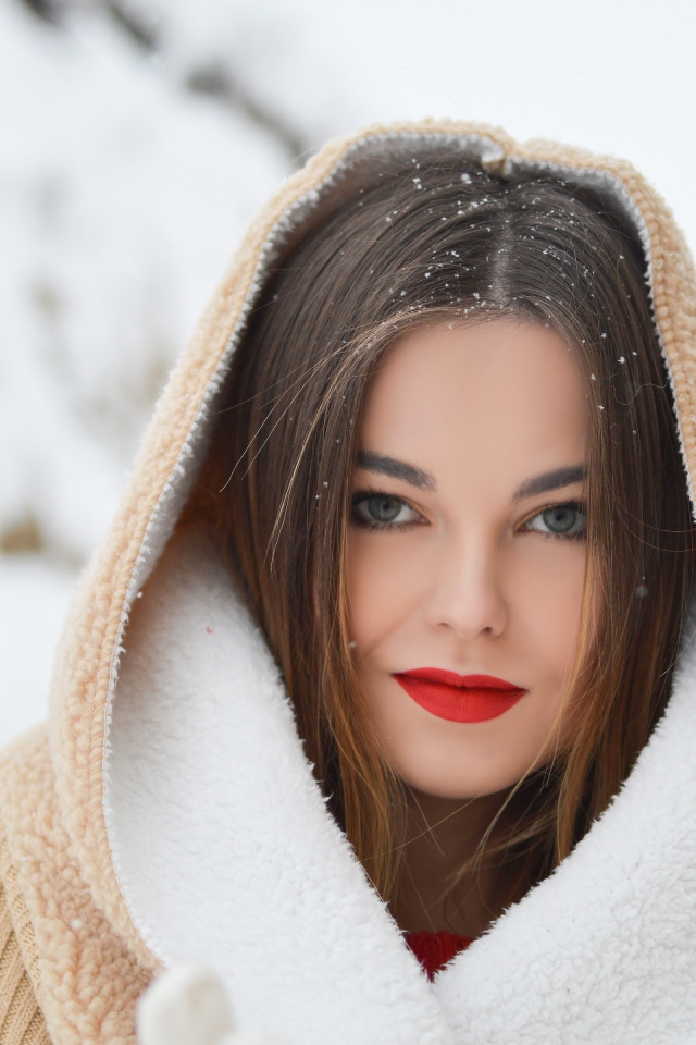 Красивая девушка с красными губами в теплой куртке зимой