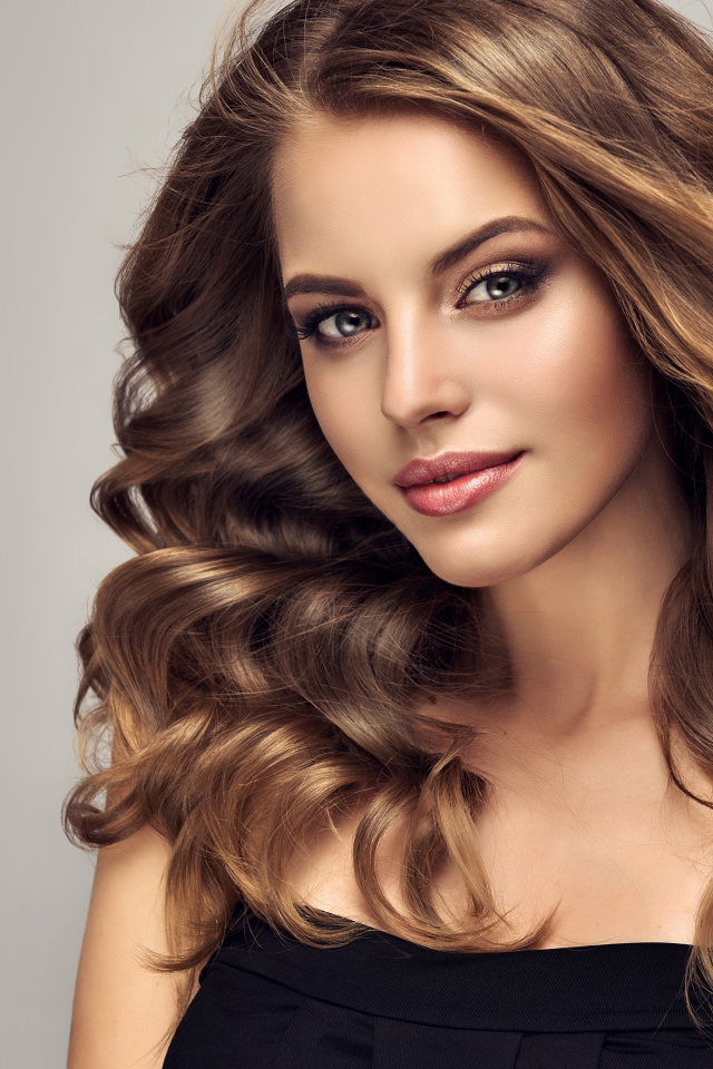 Красивая длинноволосая шатенка на сером фоне