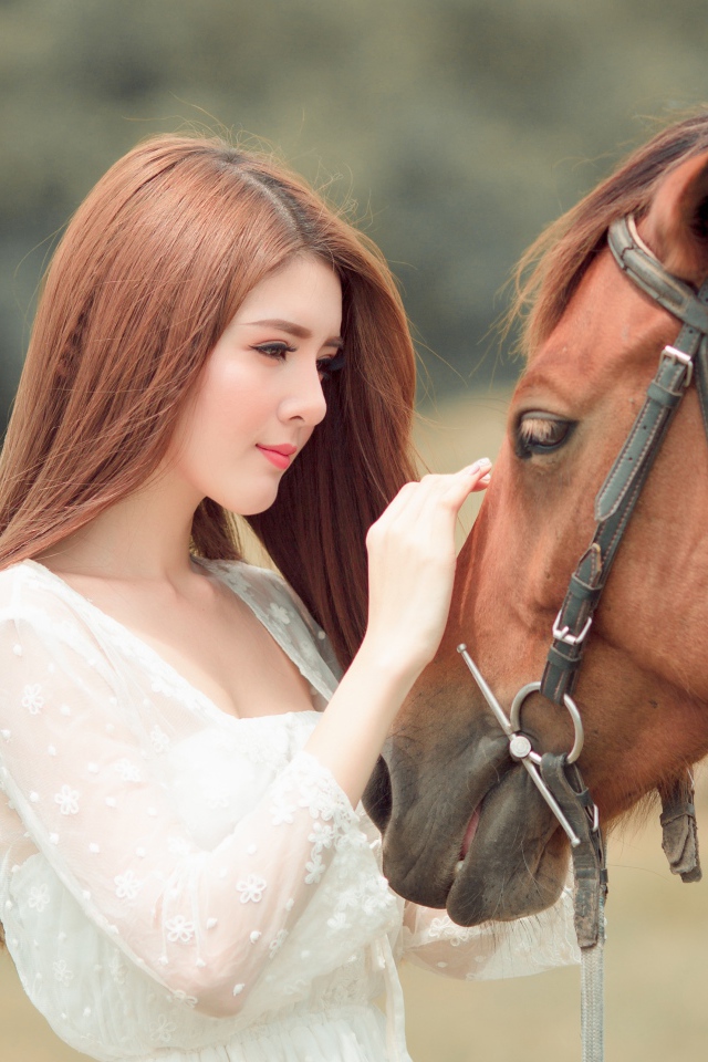 Красивая длинноволосая азиатка гладит лошадь