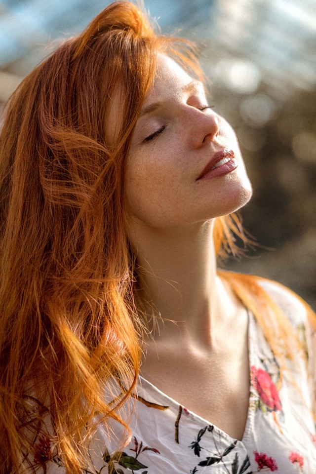 Красивая рыжеволосая девушка нежится в лучах солнца
