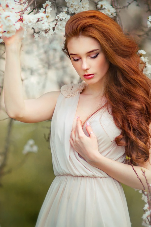 Красивая рыжеволосая девушка у цветущего дерева абрикоса 