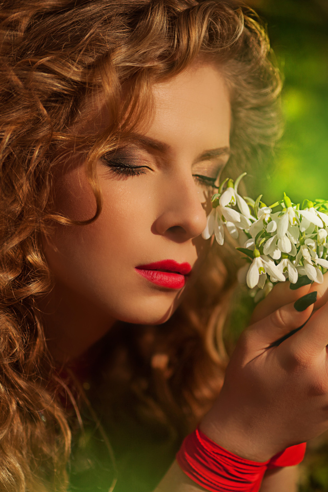 Красивая рыжеволосая девушка с букетом подснежников в руках