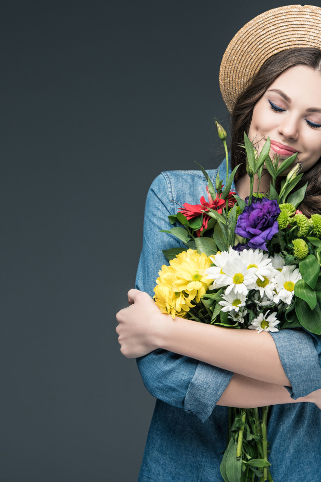 Красивая улыбающаяся девушка в шляпе с букетом цветов