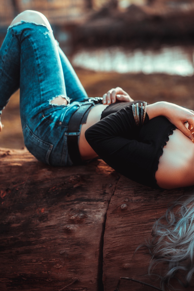 Красивая молодая блондинка лежит на сухом дереве