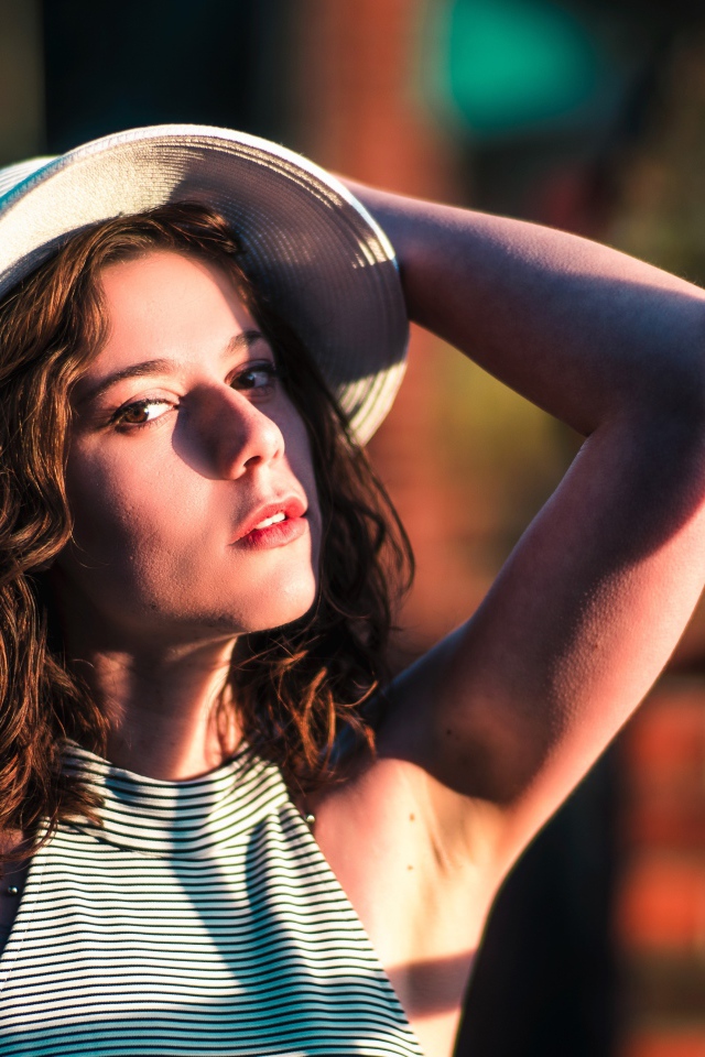 Красивая молодая девушка в белой шляпе в свете солнца