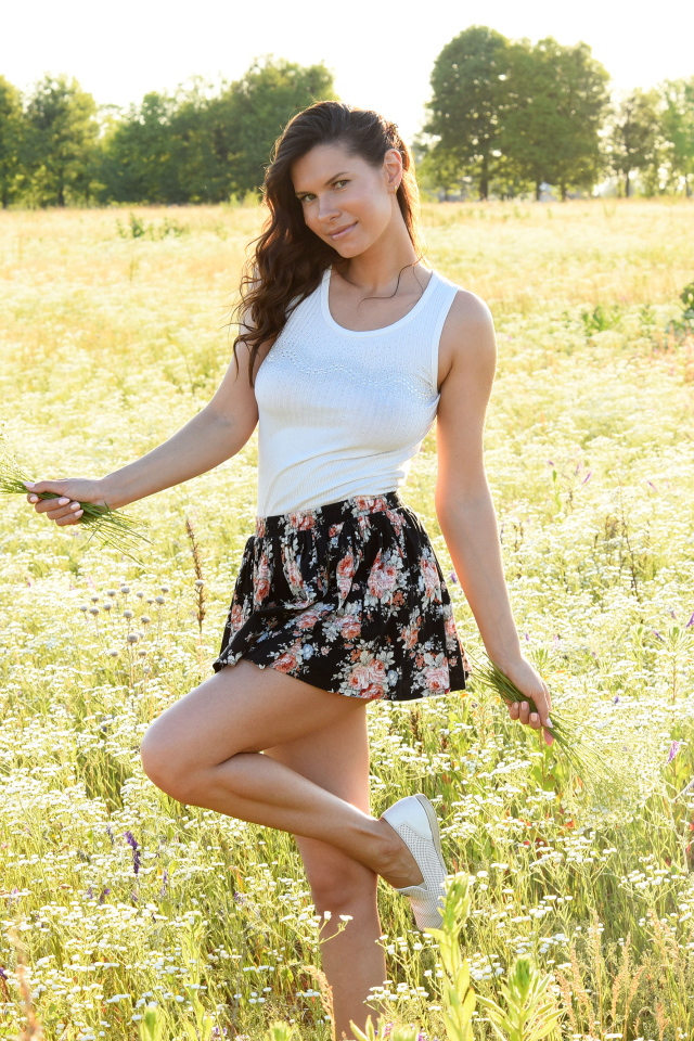 Красивая молодая девушка на поле с белыми ромашками