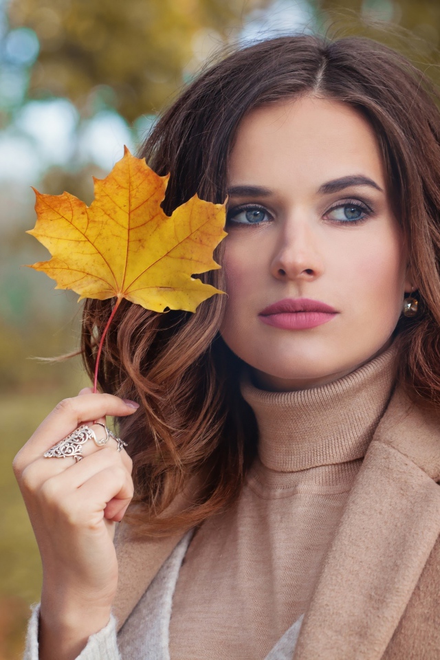 Красивая молодая девушка шатенка с желтым листом в руке