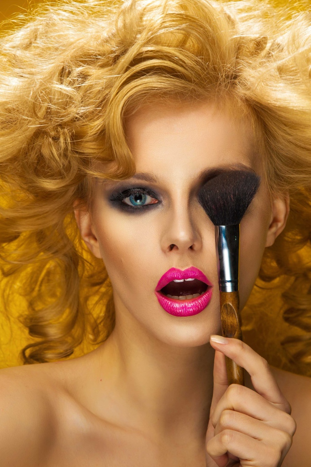 Блондинка с ярким макияжем с кистью у лица