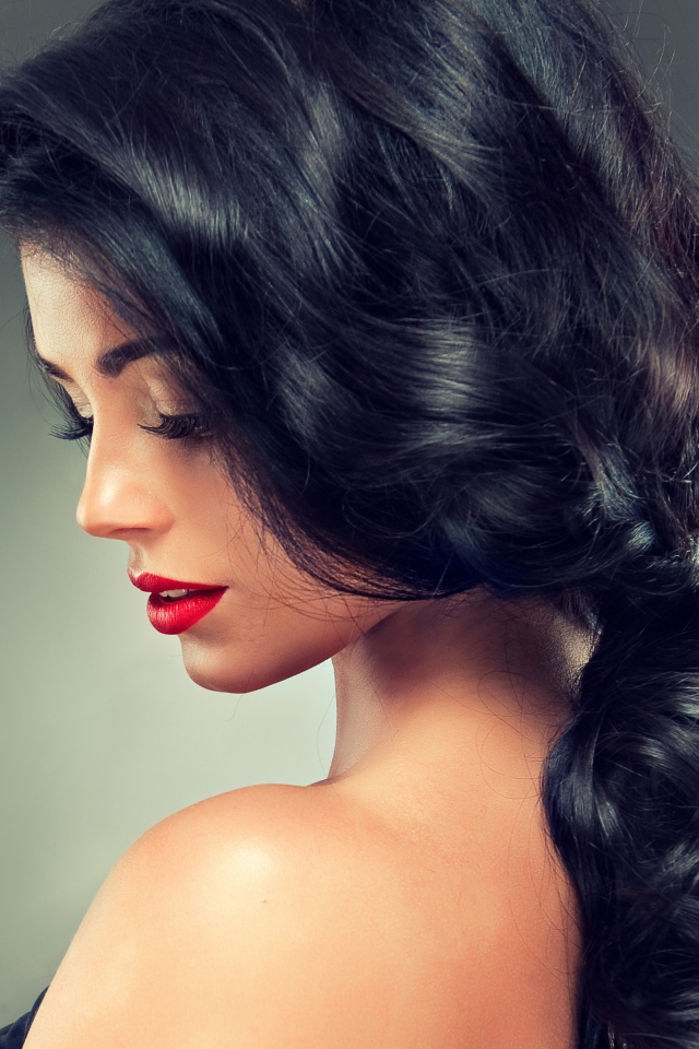 Девушка брюнетка с красивыми волосами на сером фоне