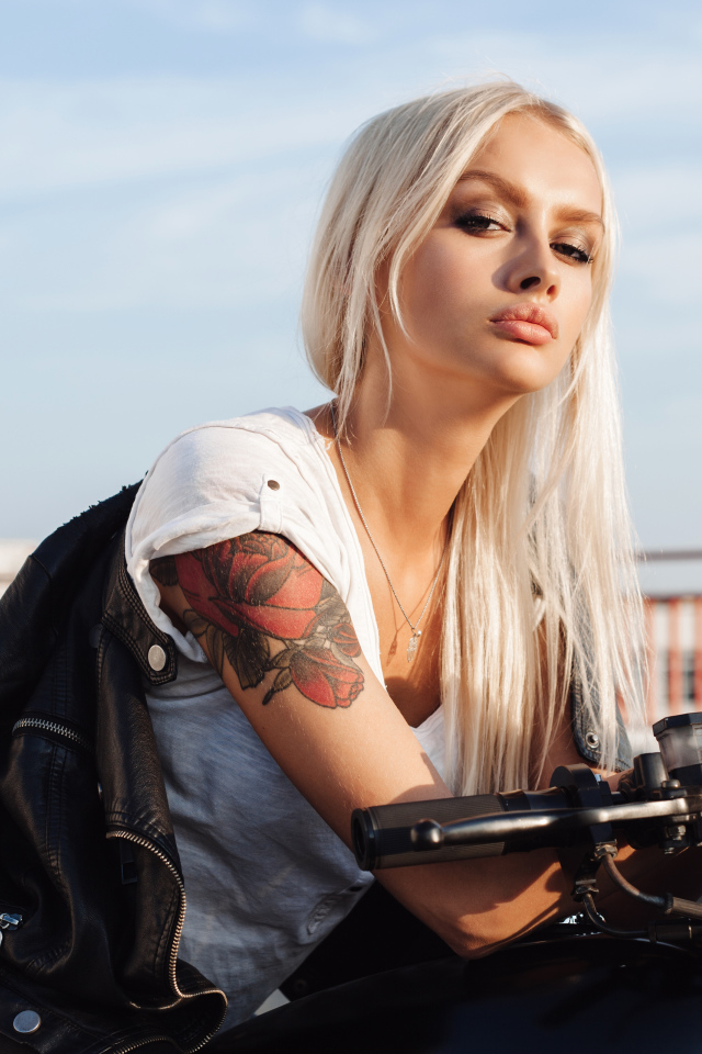 Брутальная блондинка с татуировкой на руке на мотоцикле 