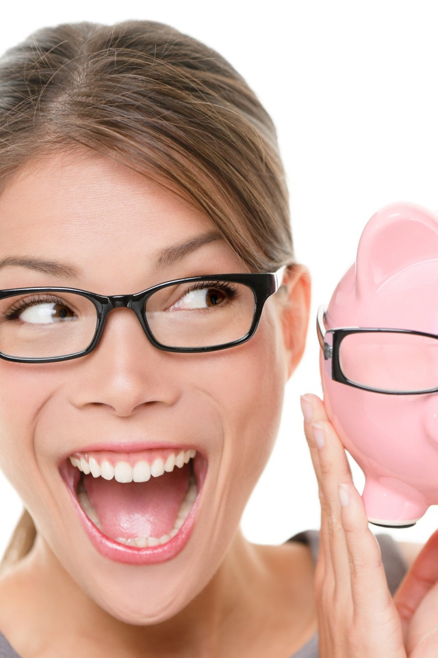 Веселая девушка в очках с копилкой в руках на белом фоне