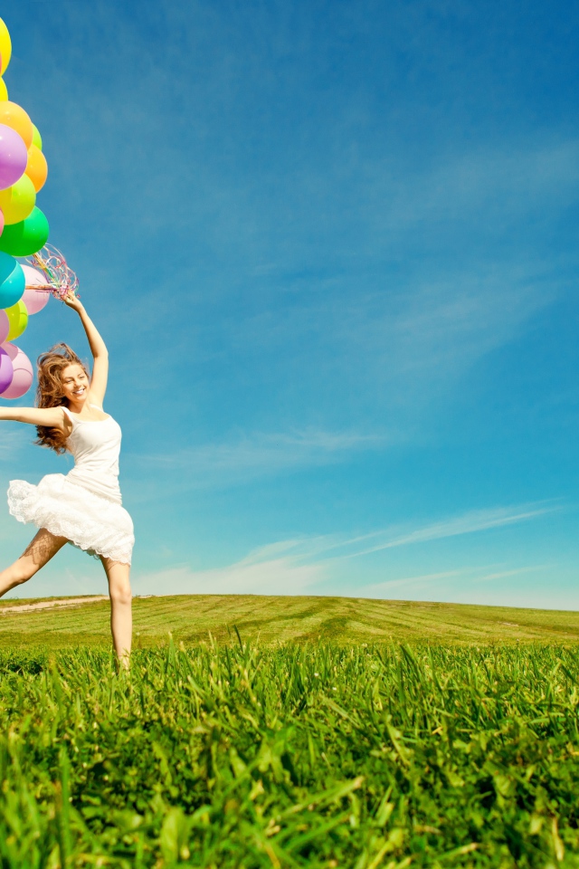 Веселая девушка в белом платье с разноцветными воздушными шариками