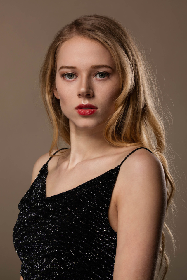 Нежная девушка модель в черном платье на сером фоне