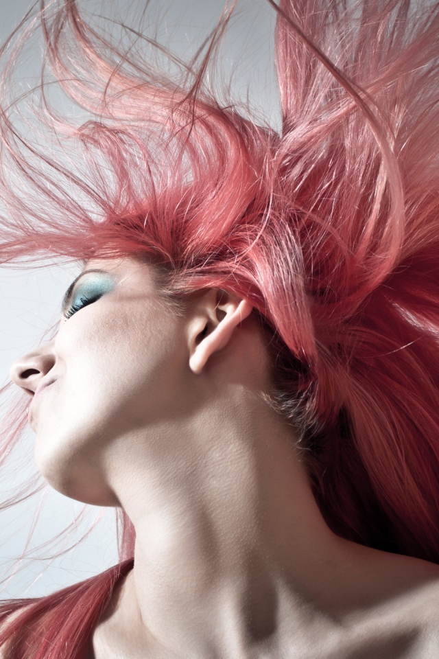 Девушка с распущенными розовыми волосами на сером фоне