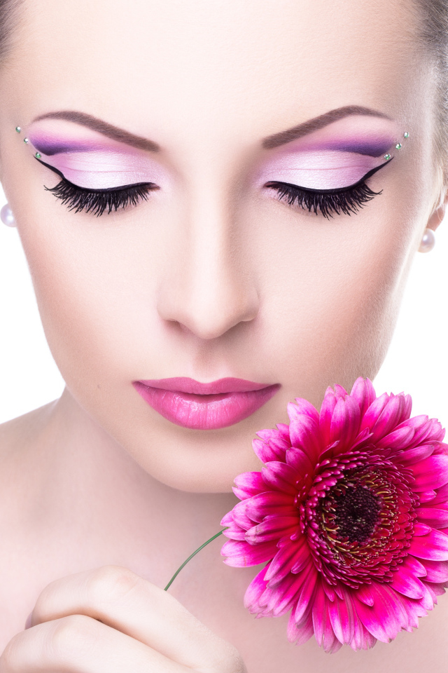 Девушка модель с нежным макияжем с розовым цветком герберы в руке