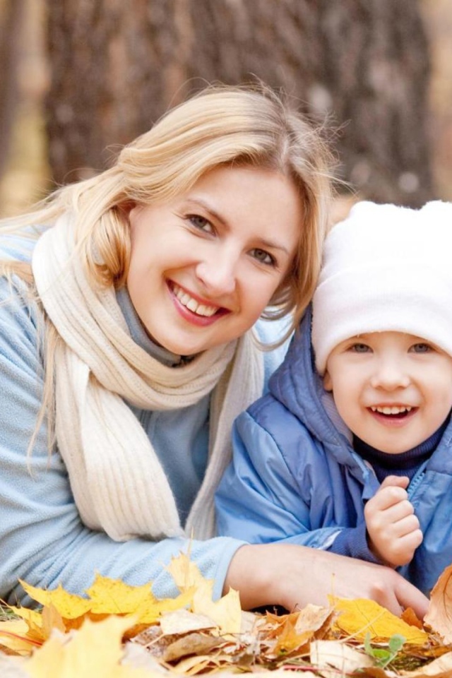 Мать с сыном лежат на листве осенью