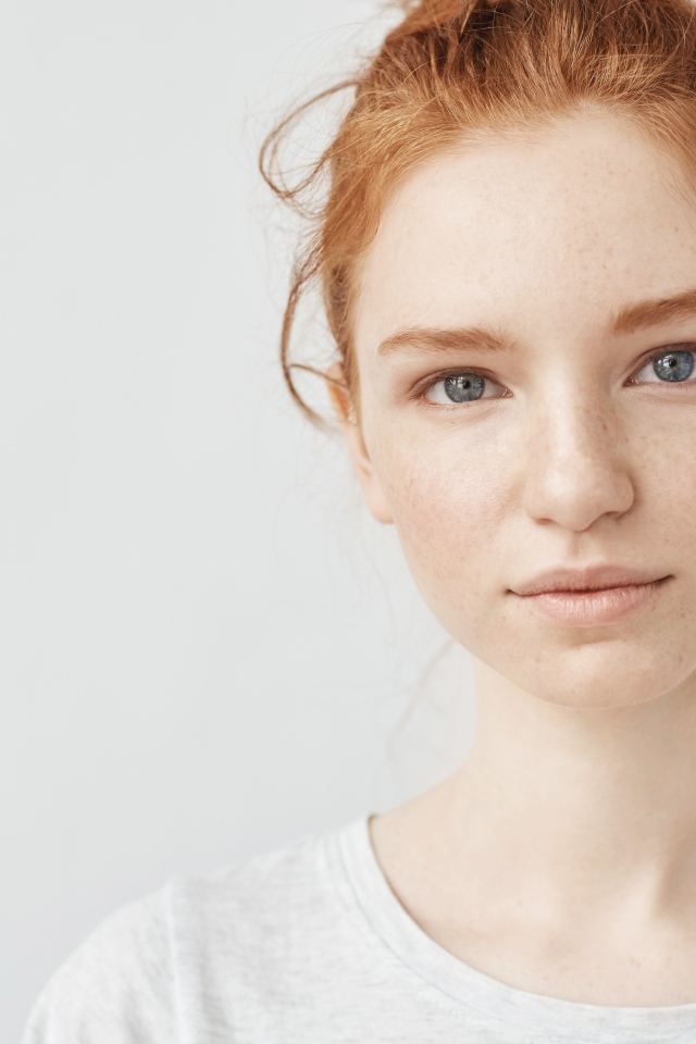Рыжеволосая девушка на сером фоне