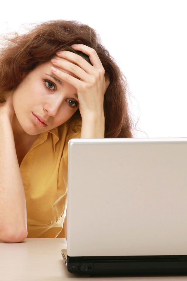 Грустная девушка сидит возле ноутбука 
