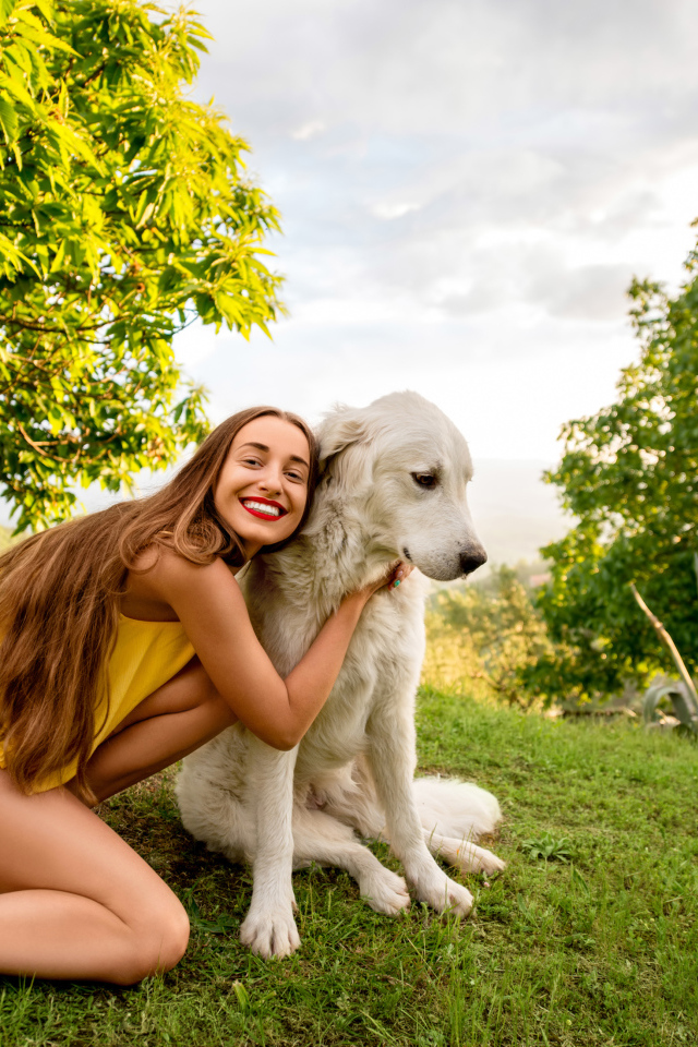 Улыбающаяся шатенка с золотистым ретривером на зеленой траве летом