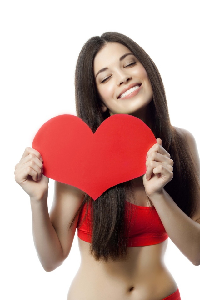 Улыбающаяся брюнетка с красным сердцем в руках на белом фоне