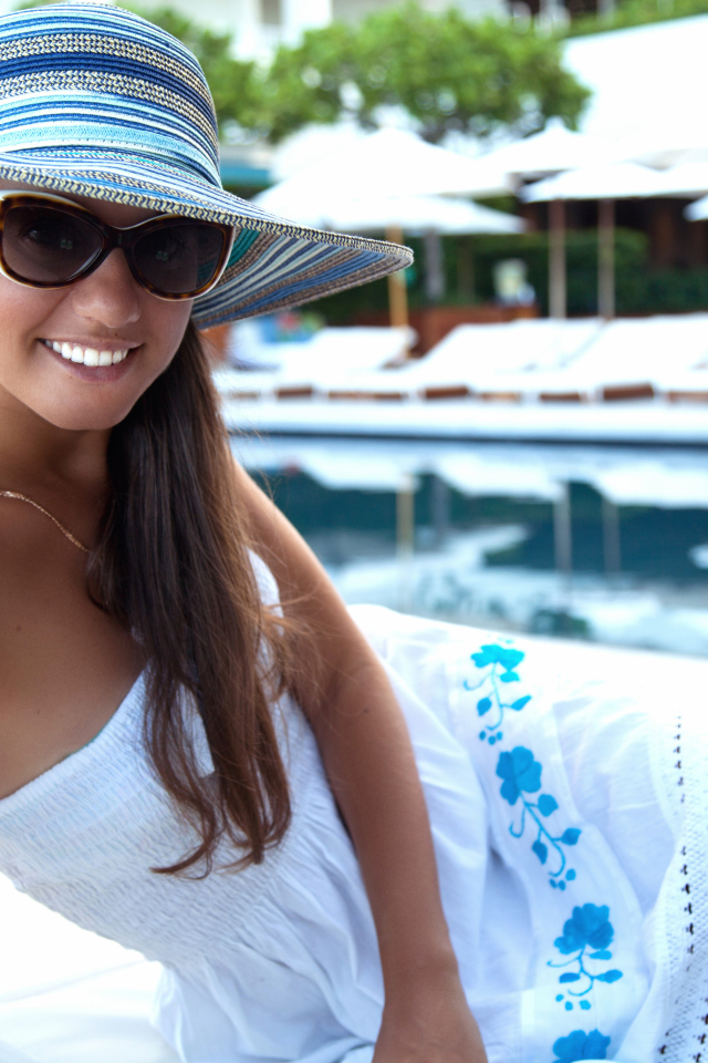 Улыбающаяся девушка в солнечных очках и шляпе у бассейна 