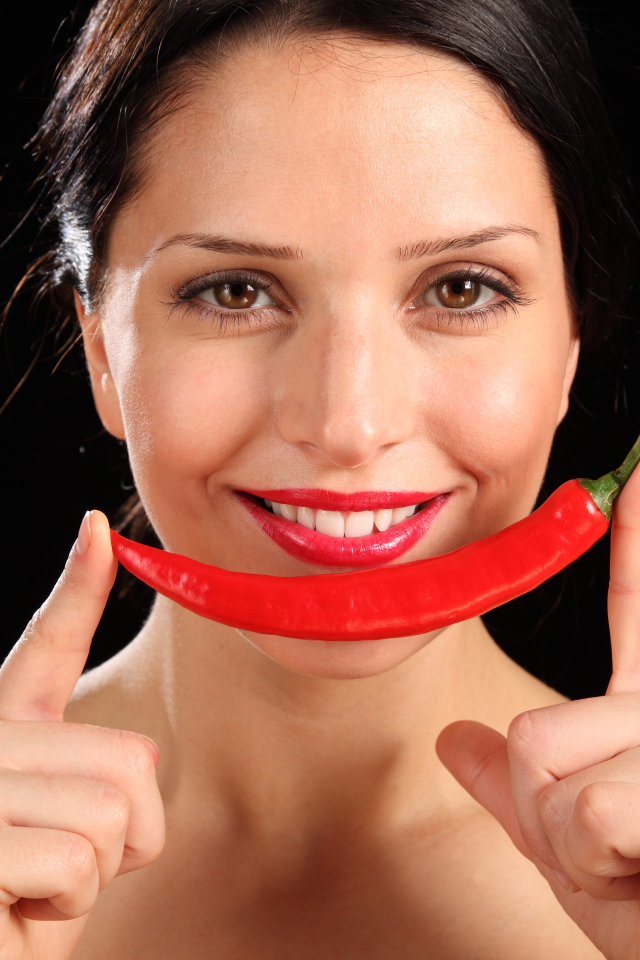 Улыбающаяся девушка с красным перцем на черном фоне