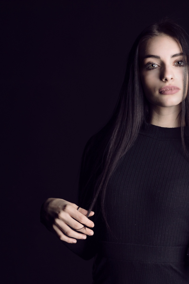 Эффектная брюнетка в черном наряде на черном фоне