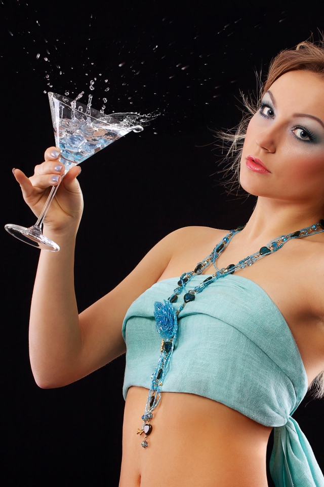 Эффектная молодая девушка с коктейлем в руках на черном фоне