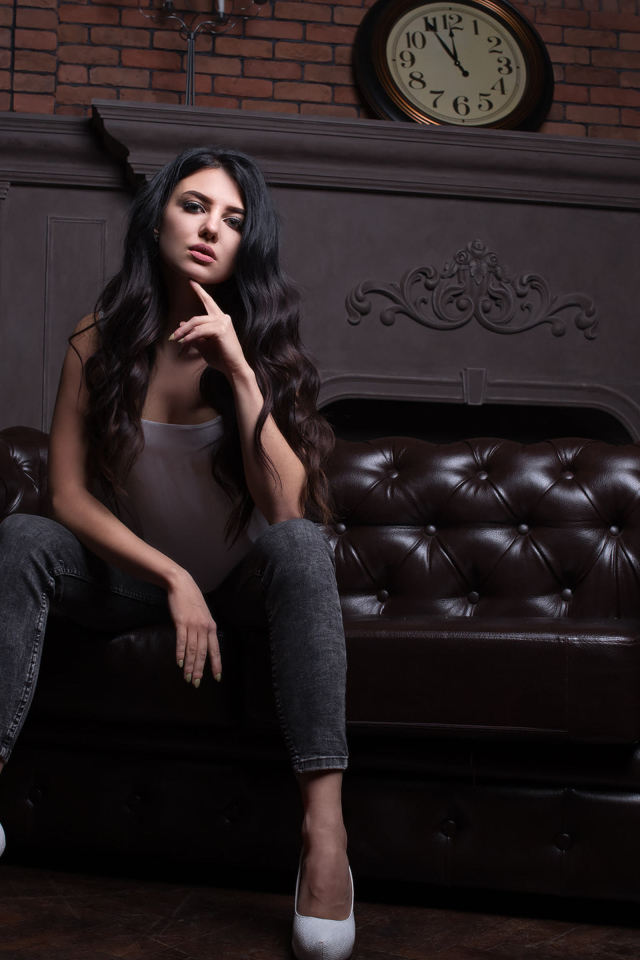 Стильная девушка сидит на кожаном диване