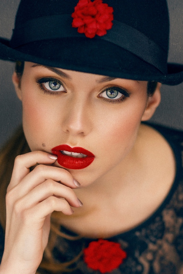 Стильная девушка с ярким макияжем в черной шляпе 