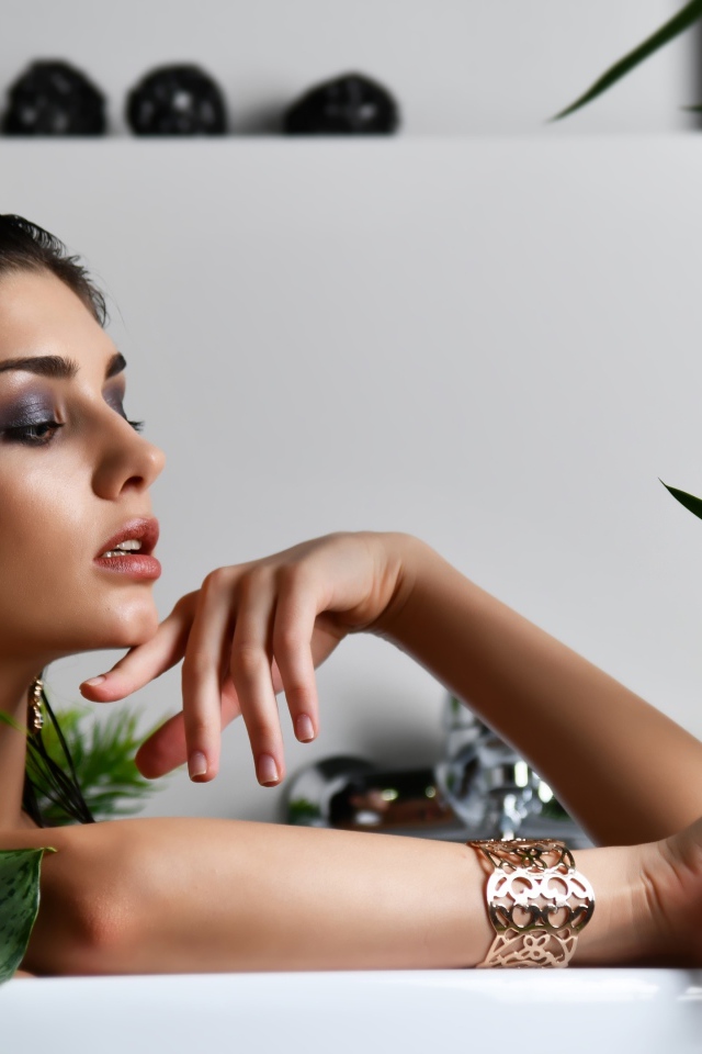 Девушка в дорогих украшения лежит в ванной