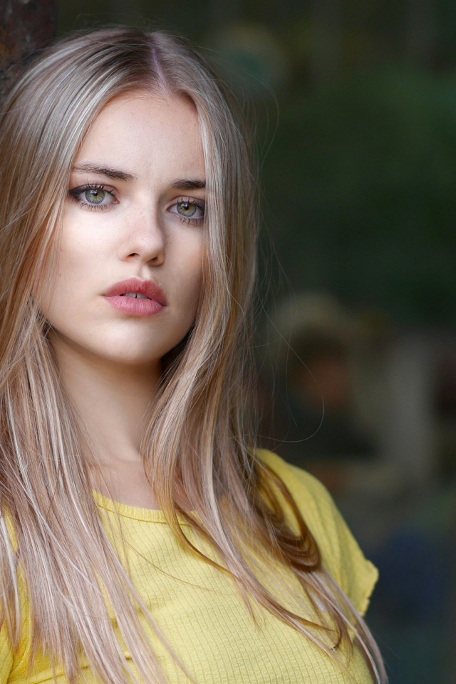 Грустный взгляд красивой светловолосой девушки у стены