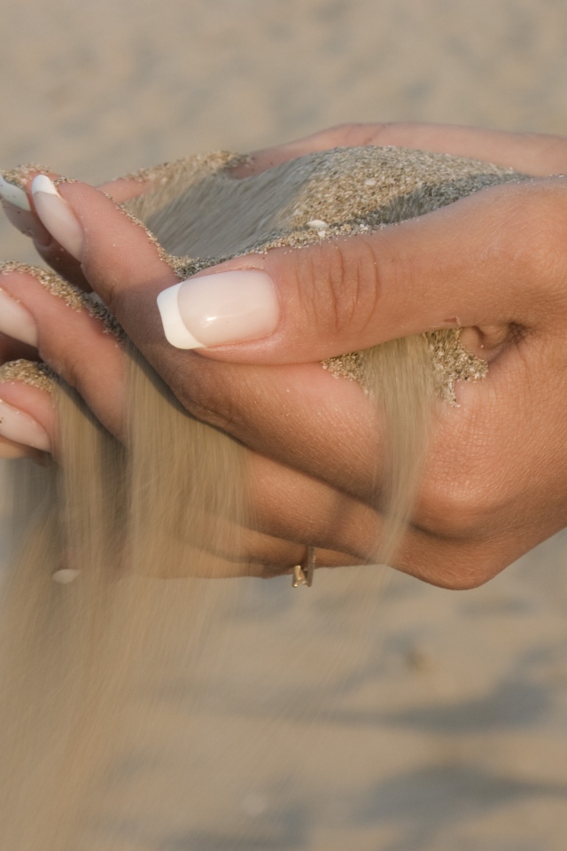 Желтый песок в руках у девушки с красивым маникюром