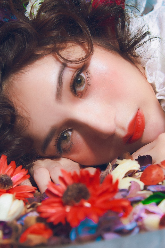Молодая красивая девушка лежит цветами в волосах