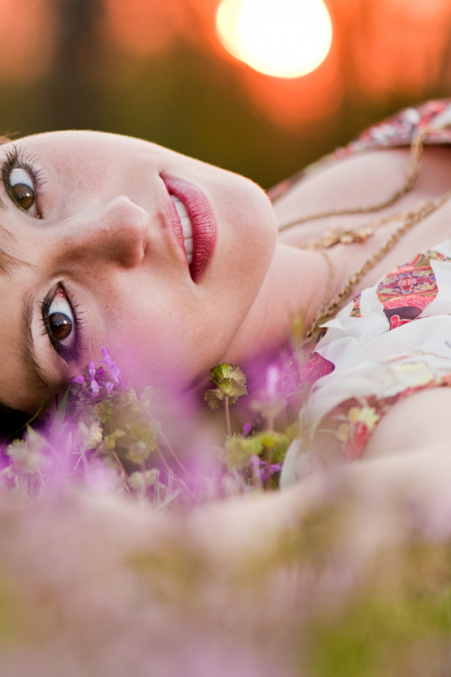 Молодая кареглазая девушка лежит на траве