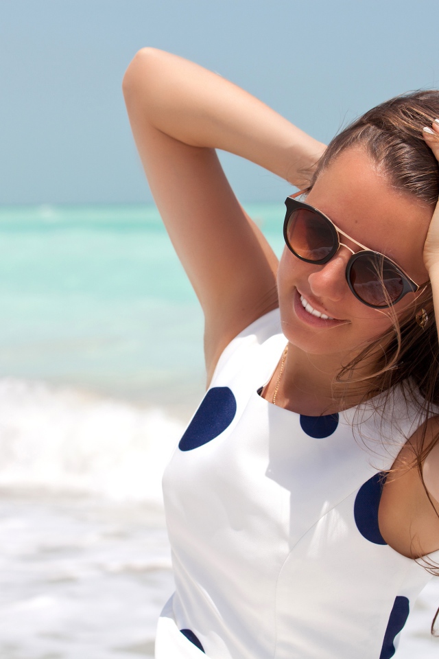 Молодая шатенка в солнечных очках у моря