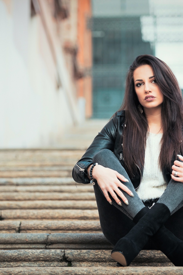 Молодая брюнетка сидит на ступеньках