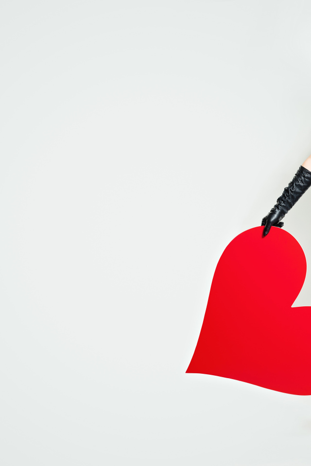 Молодая девушка в черной шляпе с красным сердцем в руке