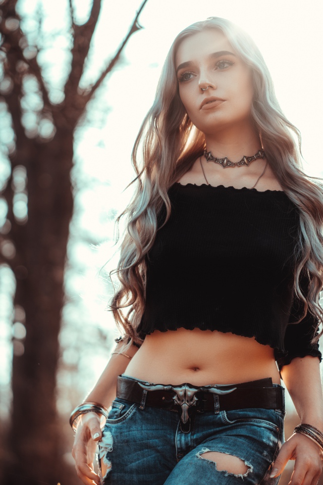 Молодая девушка в рваных джинсах с пирсингом в носу