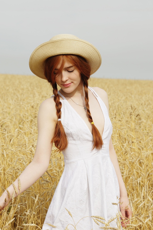 Молодая девушка в белом платье на поле с пшеницей
