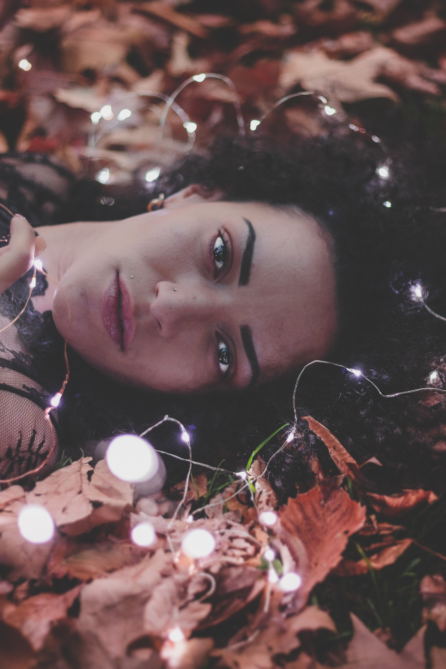 Молодая девушка лежит с гирляндой на желтых листьях