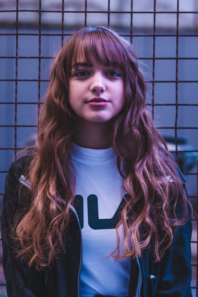 Молодая девушка на фоне железной сетки