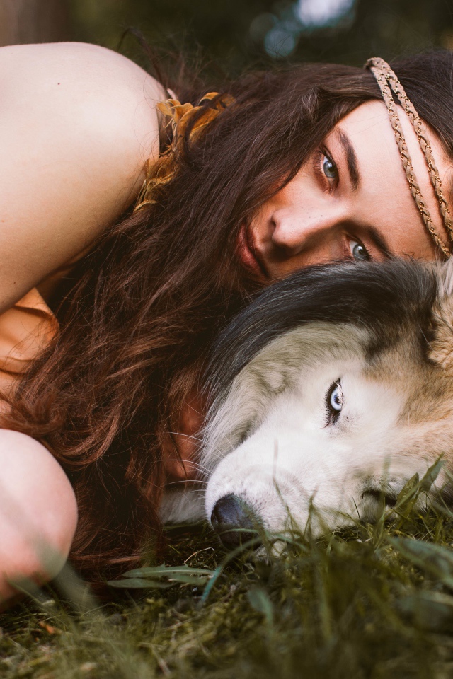 Молодая девушка с собакой породы хаски лежит на траве