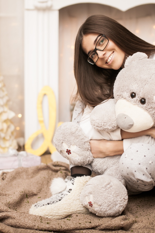 Молодая девушка в очках с плюшевым мишкой