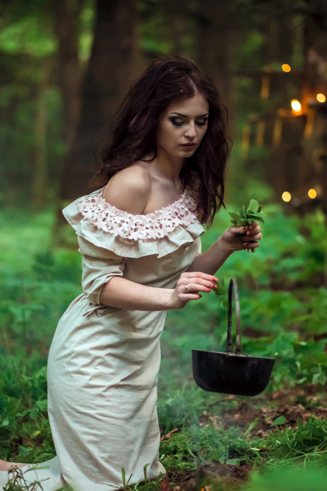 Молодая девушка колдунья варит зелье в лесу