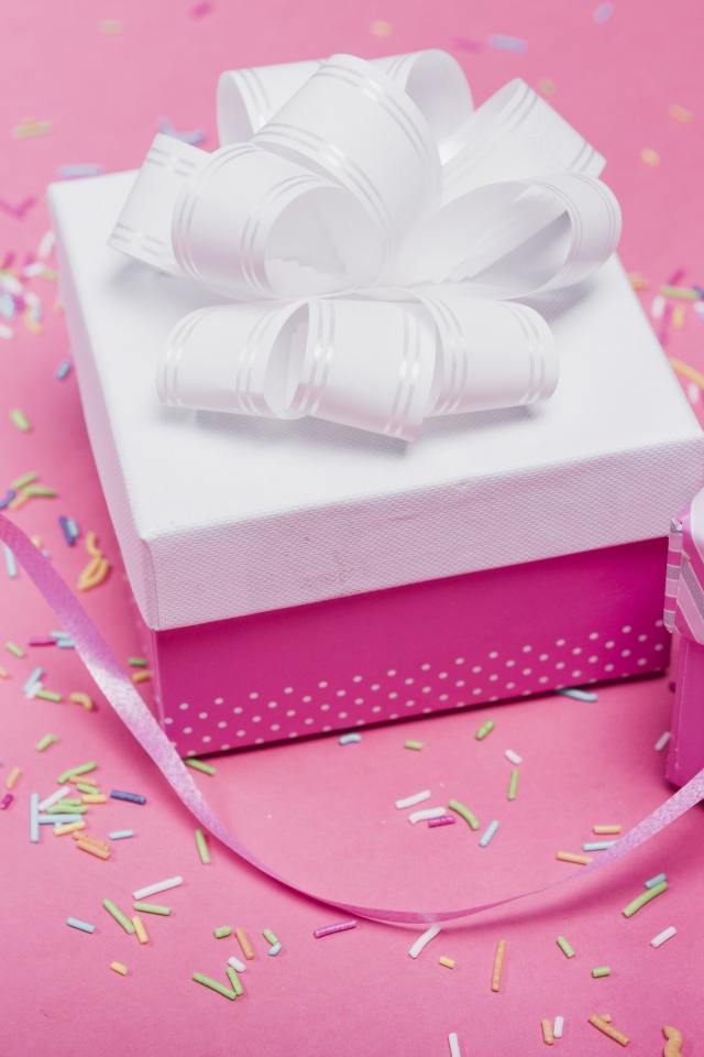 Две подарочные коробки с бантами на розовом фоне