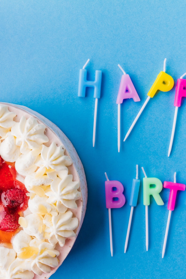 Красивый торт с кремом и клубникой на голубом фоне со свечами на день рождения