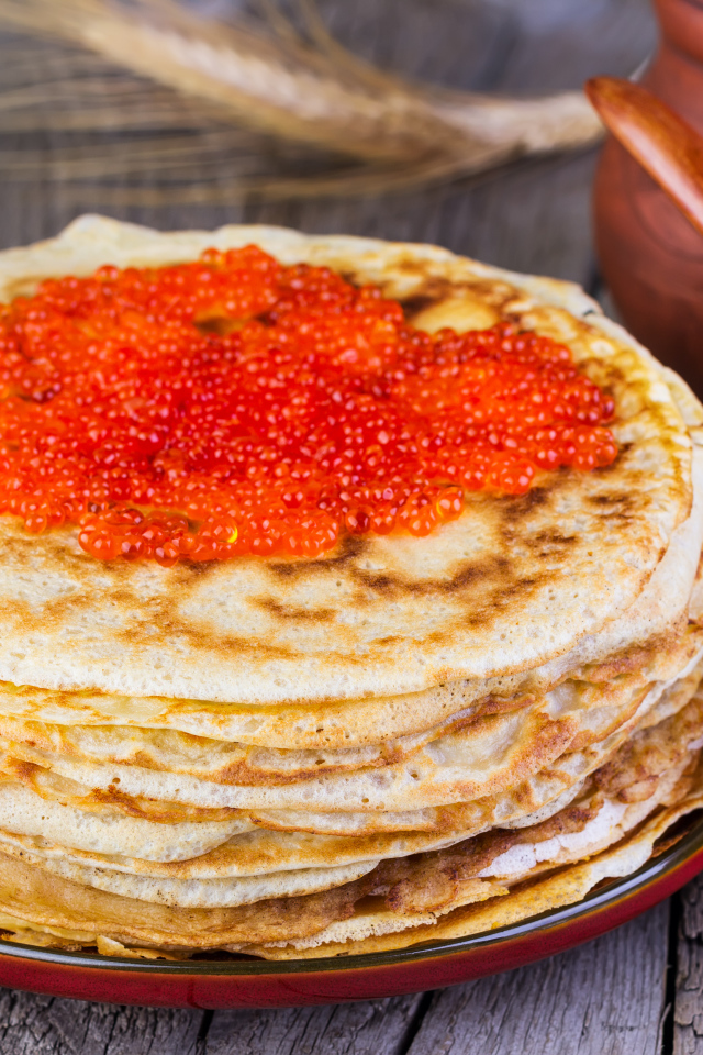 Стопка блинов с красной икрой на деревянном столе угощение на Масленицу