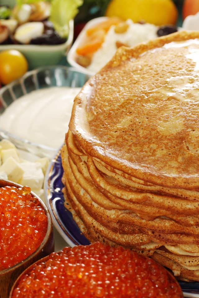 Румяные тонкие блины на столе с красной икрой на Масленицу